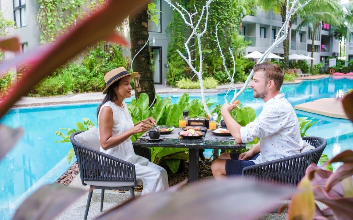 Couple having breakfast by the pool during vacation